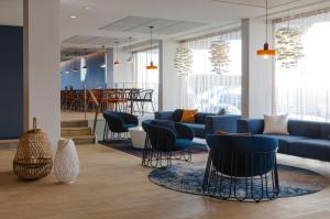 a lobby with blue couches and chairs and a table at Oceania Saint Malo in Saint Malo