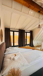 a large white bed in a room with windows at AMAO-Green I 90qm I City Center I Maisonette I Rooftop Terrace I King-Size Box-Spring Beds I EuropaPark in Lahr