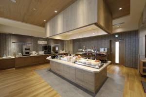 a large kitchen with a counter with food on it at Dormy Inn Maebashi in Maebashi