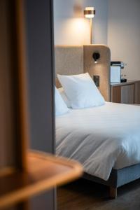 a bed with white sheets and pillows in a room at Oceania Saint Malo in Saint Malo