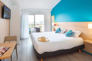 una camera d'albergo con un letto con un cappello sopra di Zenitude Hôtel-Résidences Le Cannet a Le Cannet