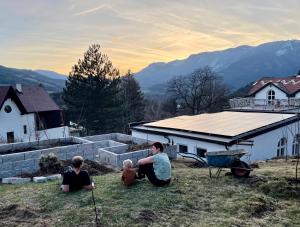 eine Gruppe von Menschen, die auf dem Gras vor einem Haus sitzen in der Unterkunft Waldschlössl Schneedörfl in Reichenau