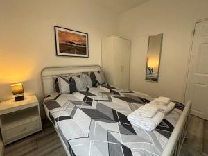 a bedroom with a large bed with black and white at Charming 2BR Cottage - Fully Furnished - 10min LGW - Free Parking in Crawley