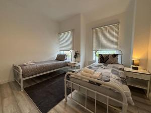 ein Schlafzimmer mit einem Bett und zwei Fenstern in der Unterkunft Charming 2BR Cottage - Fully Furnished - 10min LGW - Free Parking in Crawley