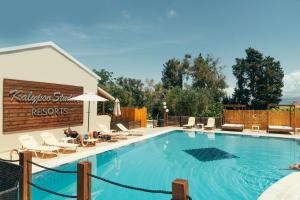 a large swimming pool with chairs and a sign at Calypso Resort Kavos in Kavos