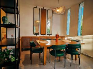 Beit Mema في Aḑ Ḑahr: غرفة طعام مع طاولة خشبية وكراسي خضراء