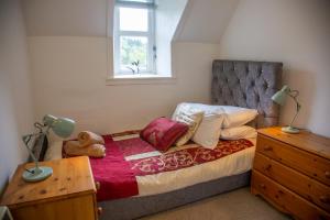 a bedroom with a bed and a dresser and a window at 6 Wheelhouse Apartments in Lairg