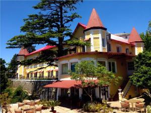 a large yellow building with a tree in front of it at WelcomHeritage Kasmanda Palace in Mussoorie