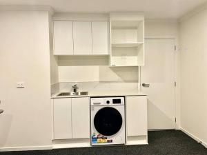 a kitchen with white cabinets and a washing machine at Nice 3 bedroom Townhouse U2 in Hamilton