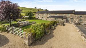 una vista exterior de una casa de piedra con una valla blanca en New Harborough Farm en Brassington