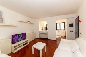 a white living room with a white couch and a tv at Il nido appartamento nel cuore del centro storico in Luino