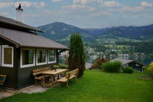 una casa con una mesa y bancos en el césped en Kantor Lodges & Chalets, en Millstatt