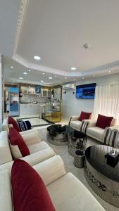 una gran sala de estar con sofás blancos y almohadas rojas. en واحة الجنوب للشقق المخدومة, en Khamis Mushayt