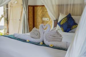 two towel swans sitting on top of a bed at Made Taro - Menjangan Homestay in Banyuwedang