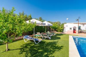 a yard with chairs and an umbrella and a pool at Casa Rural Carmo in Carmona