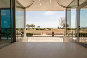 eine offene Lobby mit Glastüren und Blick auf ein Feld in der Unterkunft Hotel Monaco in Caorle