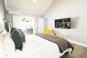 The Rose Cottage في كيب تاون: غرفة نوم مع سرير أبيض وتلفزيون على الحائط