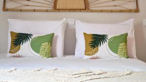 a bed with white pillows and green and gold pillows at Villa Valentina by LovelyStay in Ponta do Sol