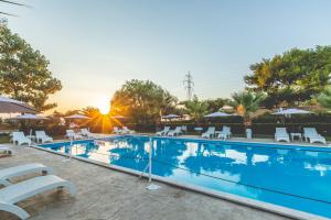 a large swimming pool with white chairs and umbrellas at La Terra Nostra in Korinthos