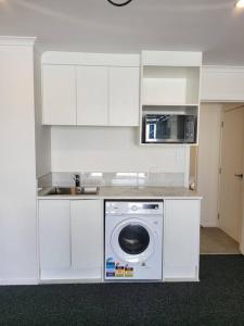 a kitchen with a washing machine and a microwave at Nice New 3 bedroom Townhouse U4 in Hamilton