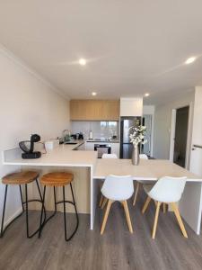 a kitchen with a white counter and some stools at Nice New 3 bedroom Townhouse U4 in Hamilton