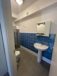 Baño de azulejos azules con aseo y lavamanos en Hotel San Martino en Cassibile