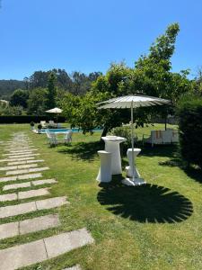 a row of tables and an umbrella in the grass at Casa Herreria in Caldas de Reis