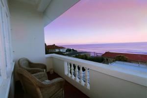 a balcony with two chairs looking out at the ocean at St James Mansions Apartment in Muizenberg