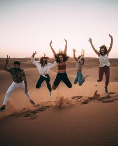 Un groupe de gens sautant dans le désert dans l'établissement Opulent Sahara Camp, à Merzouga