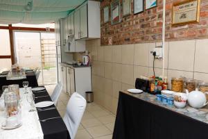 a kitchen with a long table with white chairs at Rainbow Guest House and Tours in Uitenhage