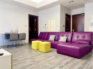a purple couch in a living room with yellow stools at Fabulous Residential Private Apartment Upgraded Full Sea & Mangrove Views Abu Dhabi - Not Hotel - 1106 in Abu Dhabi