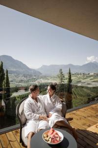 Ein Mann und eine Frau sitzen auf einem Balkon mit einem Teller Essen in der Unterkunft Feel good Resort Johannis in Dorf Tirol