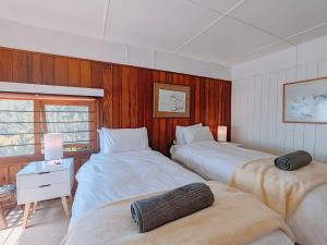 a bedroom with two beds and a desk with a computer at Timber's Ocean House in Simonʼs Town