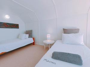 two beds in a room with a small table at Timber's Ocean House in Simonʼs Town