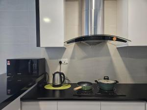 a kitchen with a stove with a pot and a microwave at Kuching Vivacity Jazz 1 Netflix in Kuching