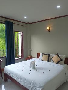 Un dormitorio con una gran cama blanca y una ventana en Dokchampa Hotel en Vang Vieng