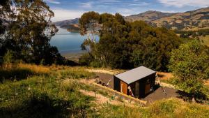 a small cabin on a hill next to a lake at Kukupa Puni at Akaroa Lavender in Duvauchelle