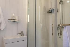 a white bathroom with a shower and a sink at Kukupa Puni at Akaroa Lavender in Duvauchelle