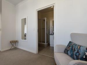 a living room with a couch and a mirror at Courtside Views Empire Apartment in Muizenberg
