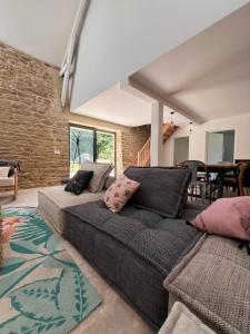 a living room with a couch and a brick wall at La grange - Grande longère à moins de 30 minutes des plages in Plumelec