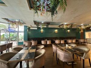 金夏沙的住宿－Hotel Belle Vie，一间带桌椅和绿色墙壁的餐厅