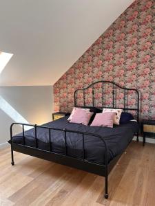 a black bed with pink pillows in a bedroom at La grange - Grande longère à moins de 30 minutes des plages in Plumelec