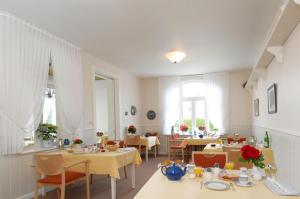 - une salle à manger avec des tables, des chaises et des fenêtres dans l'établissement Pension Hilligenlei Wohnung Langeness, à Wyk auf Föhr