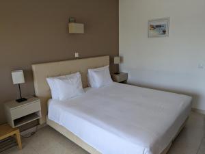 una camera da letto con letto, lenzuola e cuscini bianchi di Vivenda Solmar a Lagos