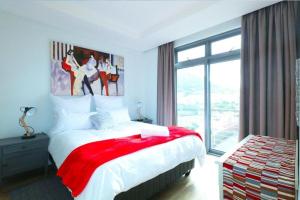 1 dormitorio con 1 cama grande con manta roja en Sea Life Muizenberg, en Muizenberg