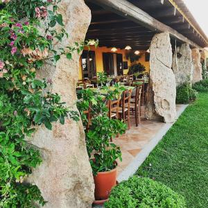 ein Restaurant mit Steinmauern, Tischen und Pflanzen in der Unterkunft Agriturismo Lu Nodu in Greuli 