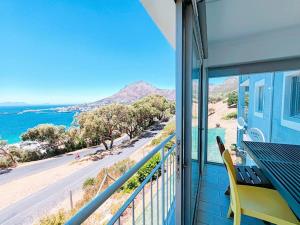 a balcony with a table and chairs and a view of the ocean at Bay Views in Simonʼs Town