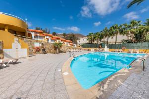 - une piscine dans un complexe avec des palmiers dans l'établissement Apartamentos Punta Marina by LIVVO, à Morro del Jable