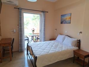 a bedroom with a bed and a table and a window at River Studios & Apartments in Mesongi