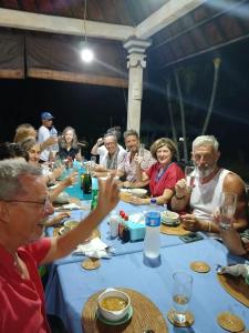 un grupo de personas sentadas en una mesa comiendo en Coral Bay Bungalows Amed Bali, en Amed